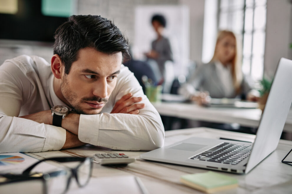 Young,Businessman,Leaning,On,His,Desk,And,Feeling,Bored,While