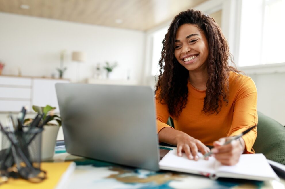 Distance,Education.,Portrait,Of,Smiling,Woman,Sitting,At,Desk,,Using