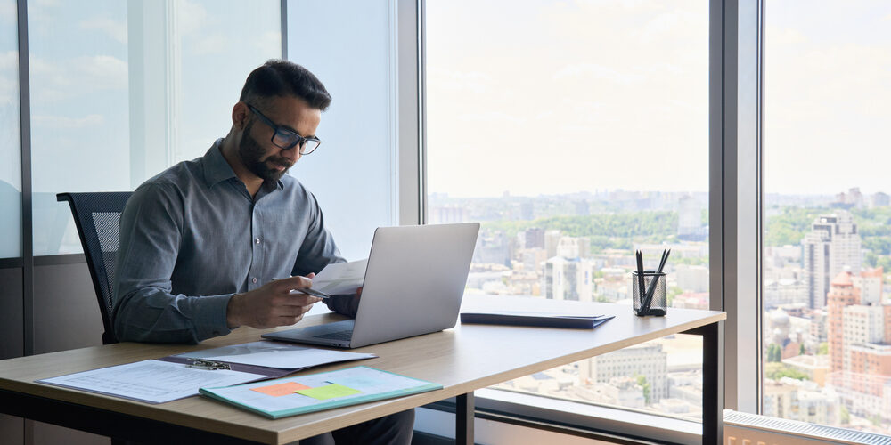 Indian,Latin,Focused,Financier,Sitting,At,Desk,Doing,Paperwork,Working